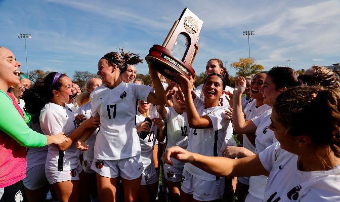 Madison Ibale lifts the NCAA West Regional trophy as SPU players celebrate reaching the quarterfinals of the NCAA Tournament.