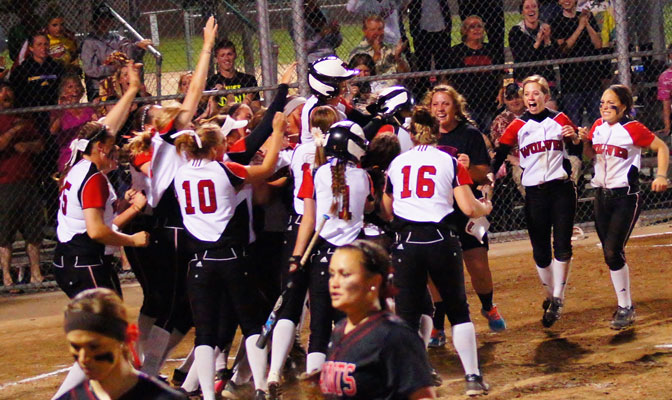 WOU mobs Jourdan Williams at home plate after her eighth-inning two-run home run won the game for the Wolves (Photo by Jeffrey Gaca).